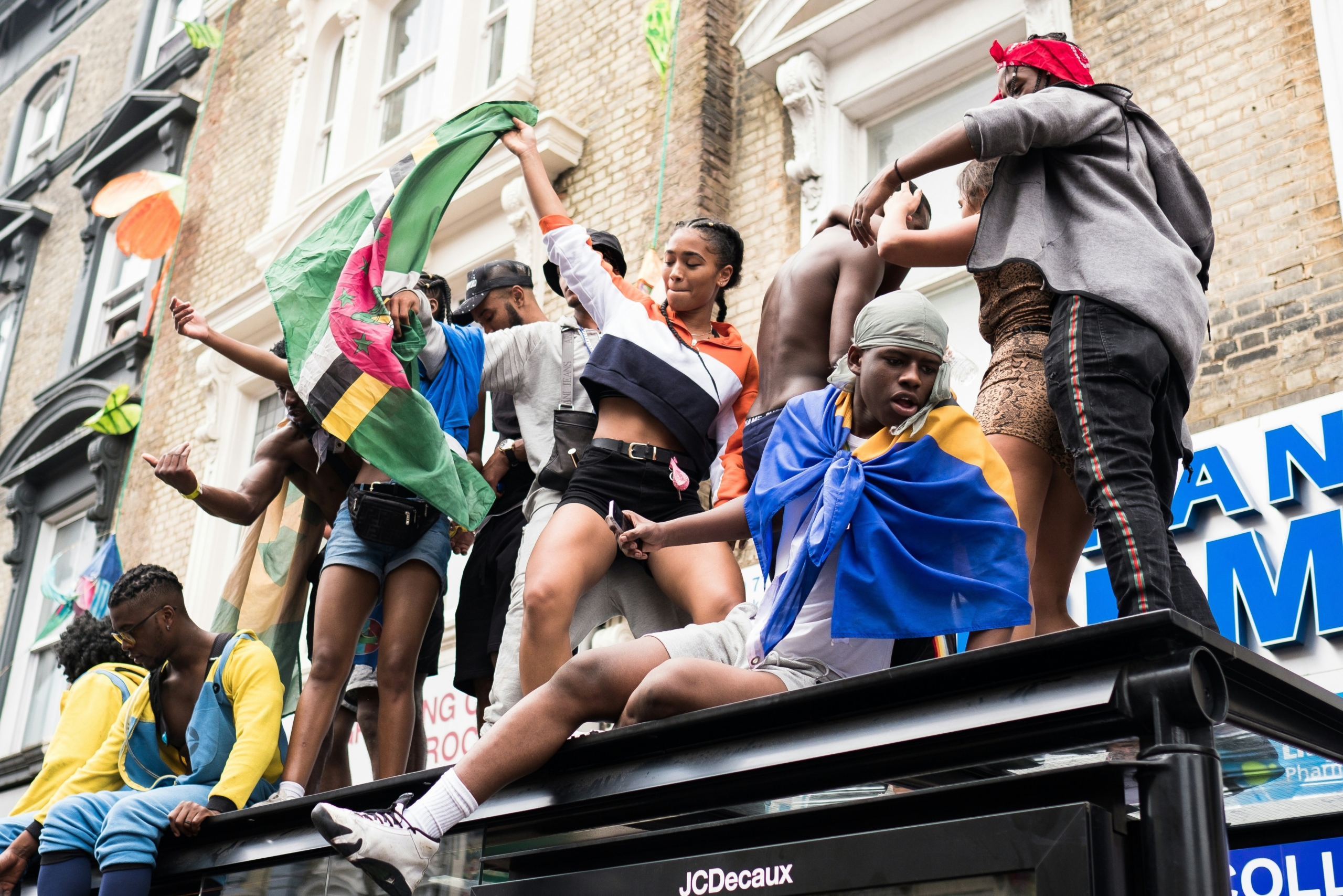 People waiving flags and dancing on top of a bus stop