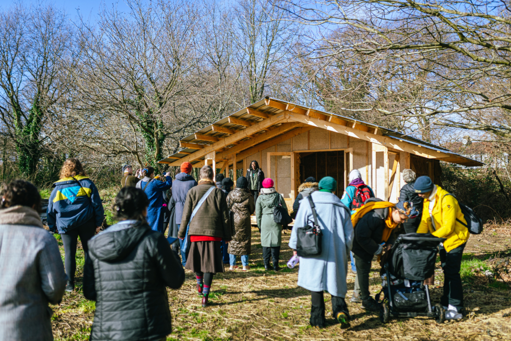 People standing in front of a little wood house